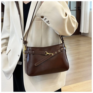 Détail d'un sac à bandoulière vintage marron foncé avec boucles dorées et cuir poli brillant