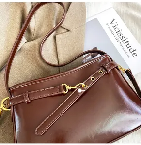 Gros plan détaillé d'un sac bandoulière en cuir marron foncé avec boucles dorées et œillets