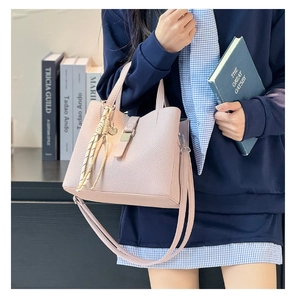 Detail of pink pebbled leather bucket bag featuring gold hardware and tassel charm