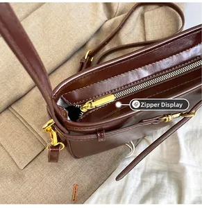 Détail de la fermeture éclair dorée sur un sac à bandoulière en cuir marron foncé