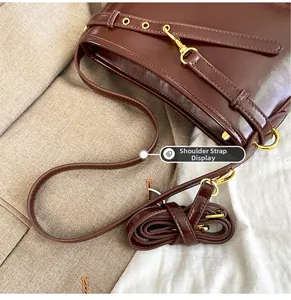 Détail de la bandoulière réglable avec garnitures dorées sur un sac cabas en cuir marron