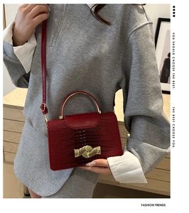 Close-up of wine red lizard texture handbag with golden wave buckle and metal handle
