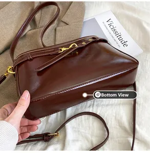 Vue détaillée du fond et du côté du sac en cuir marron foncé avec boucles dorées