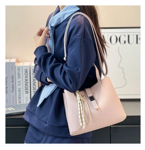 Detailed side view of a light pink lychee grain leather bucket bag with tassel detail