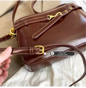 Détail du sac en cuir marron brillant avec bandoulière réglable et ferrures dorées