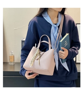 Detailed shot of litchi grain pink bucket bag with elegant silk scarf and buckle closure