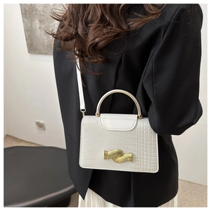 Detail of white lizard pattern handbag featuring gold semi-circle handle and twist lock