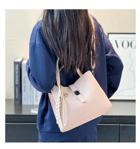 Detailed close-up of pink pebbled leather bucket bag with heart charm and woven strap