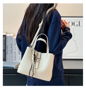 Detail of off-white bucket bag with lychee texture leather and stylish patterned silk scarf