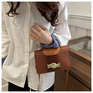 Gros plan du sac marron à motif lézard avec un fermoir doré en forme de vague