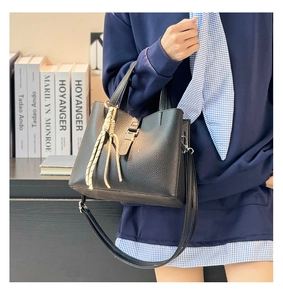Detail of black lychee grain bucket bag with metal buckle and woven rope accessory
