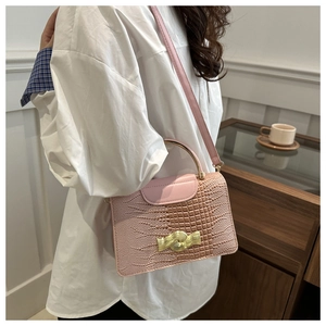 Pink faux crocodile leather handbag featuring elegant golden wavy buckle and metal handle