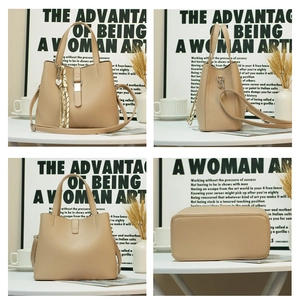 Detail view of large beige bucket bag showing front clasp, side width, and base structure