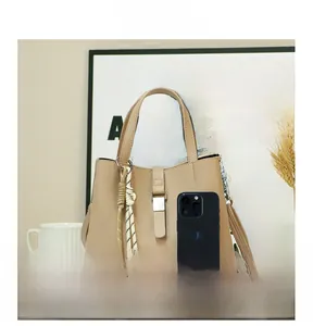 Detail of beige lychee leather bucket bag with silk scarf and smartphone for size scale