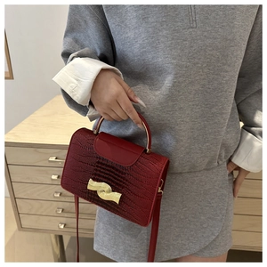 Détail du sac à main bordeaux à motif lézard avec boucle métallique dorée élégante