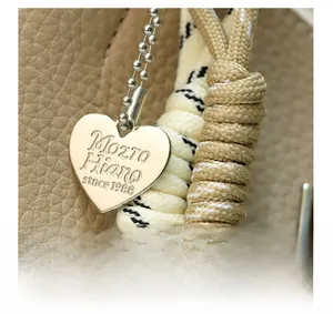 Macro detail of lychee grain leather bag with a heart-shaped silver brand tag and woven cord