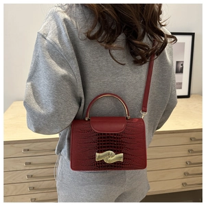 Detail of lizard pattern texture on dark red bag with gold hardware and clasp