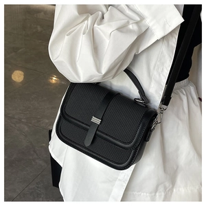 Detail of black woven texture leather crossbody bag with silver metal buckle on model