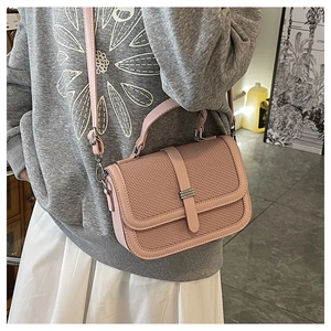 Detail of soft pink leather handbag with woven flap and stylish metal buckle closure