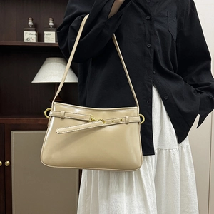 Sac à bandoulière beige en similicuir avec boucle dorée, porté par un mannequin à domicile