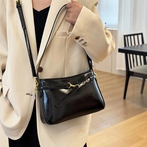 Sac fourre-tout chic en similicuir noir avec boucles dorées porté par un mannequin chic