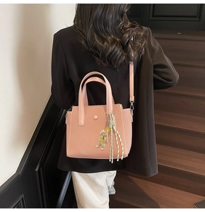Pink woven texture tote bag with cute bear charm shown in a lifestyle staircase setting