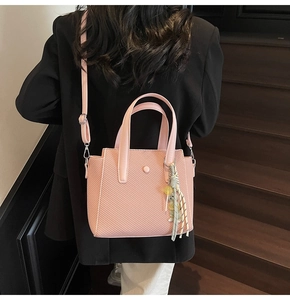 Pink woven bucket bag with floral scarf handle detail worn over a black blazer