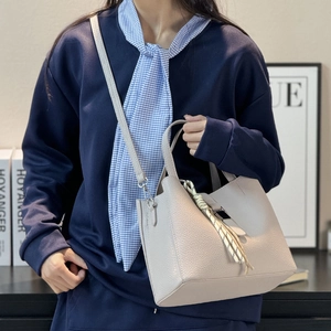 Fashionable beige bucket bag with litchi grain texture and elegant scarf accessory