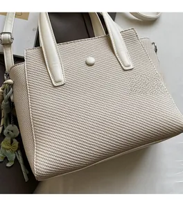 Detail of twill woven texture on beige handbag with a cute dog-shaped pendant