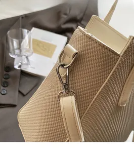 Detailed texture of woven straw bucket bag with gold hardware and white leather strap
