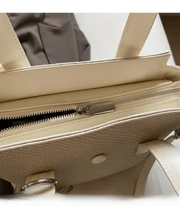 Detailed close-up of smooth silver metal zipper and woven texture on beige tote bag
