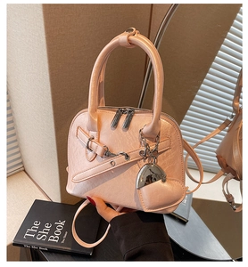 Detail view of pink shell bag with heart charm and adjustable shoulder strap