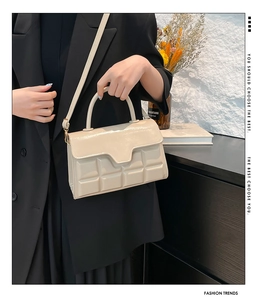 Detail der beige gesteppten Gitterhandtasche mit Glanzfinish und Goldbeschlägen