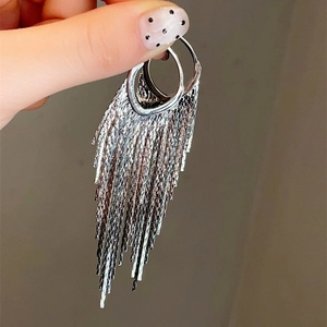 Detail of silver long tassel earrings featuring layered rings and fine metal chains