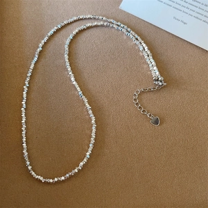 Détail du collier de perles argentées avec pendentif cœur sur cuir marron texturé