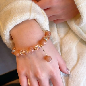 Bracciale di perline con pietra di luna arancione e cristalli sul polso di una modella