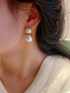 Détail de la boucle d'oreille géométrique avec disque marbré et sphère argentée mate