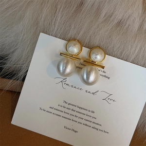 Élégantes boucles d'oreilles perles dorées présentées sur une carte cadeau blanche