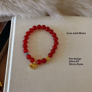 Detail of red agate bead bracelet featuring golden horse charm and coin bead