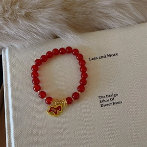 Detailed shot of a festive red agate beaded bracelet with a gold horse charm on a book