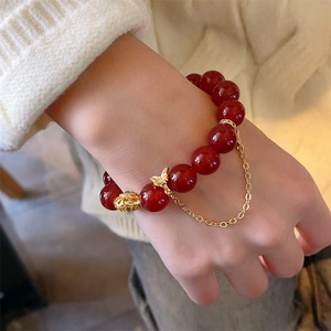 Bracelet perles agate rouge 12mm avec pendentif papillon doré porté au poignet