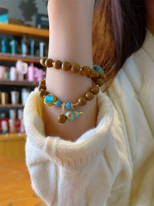 Close-up of a vintage Chinese style beaded bracelet with blue gourd pendant on a wrist