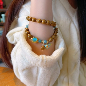 Close-up of double-layer beaded bracelet with blue gemstone pendant and enamel gourd charm