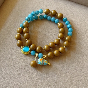 Macro detail of double-layer beaded bracelet with blue gourd charm and golden accents