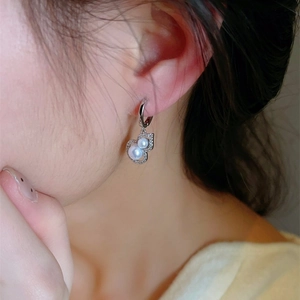 Silver pearl hoop earrings with heart-shaped crystal pendant on a female model