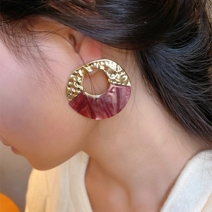 Irregular round hoop earrings featuring hammered gold metal and marbled resin texture
