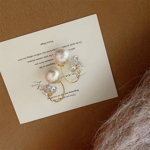 Macro detail of gold-plated snowflake pearl earrings with cubic zirconia tassels on a card