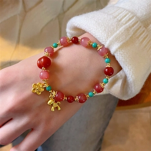 Bracelet en cristal de fraise avec pendentif cheval doré porté au poignet