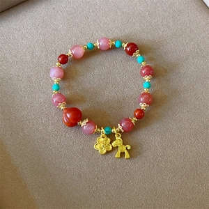 Détail de perles de quartz fraise avec breloques dorées en forme de cheval et fleur