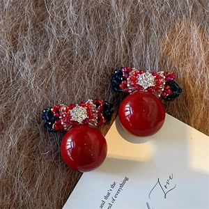 Detailed view of red bow earrings with handcrafted crystal beads and glossy sphere drop